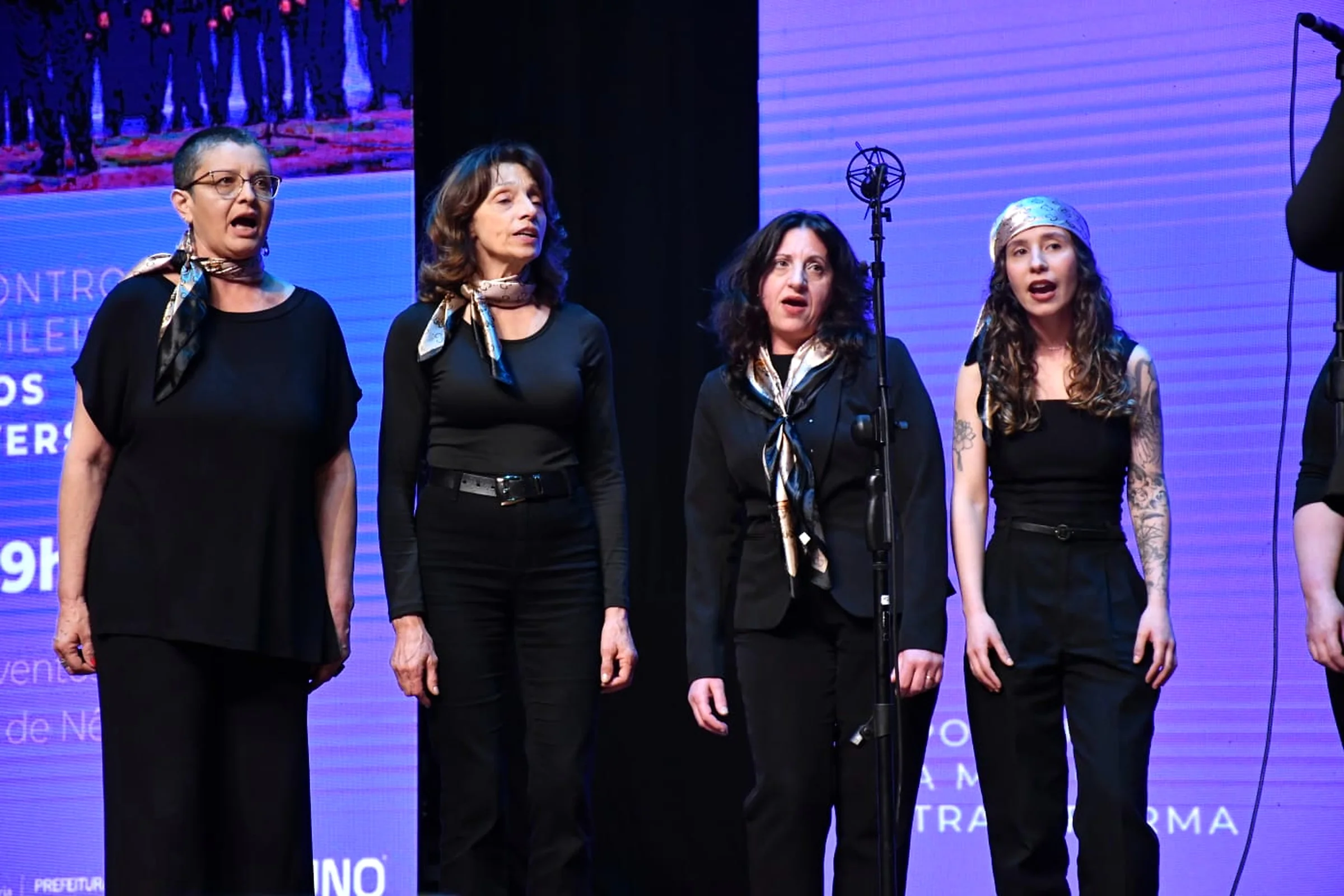 Quatro cantoras do coro, com lenços de seda; Karen à direita, de lenço dourado.